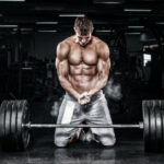 Muscular young fitness sports man workout with barbell in fitness gym