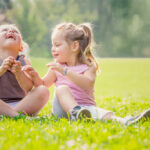 blonde smiling sister play in a garden